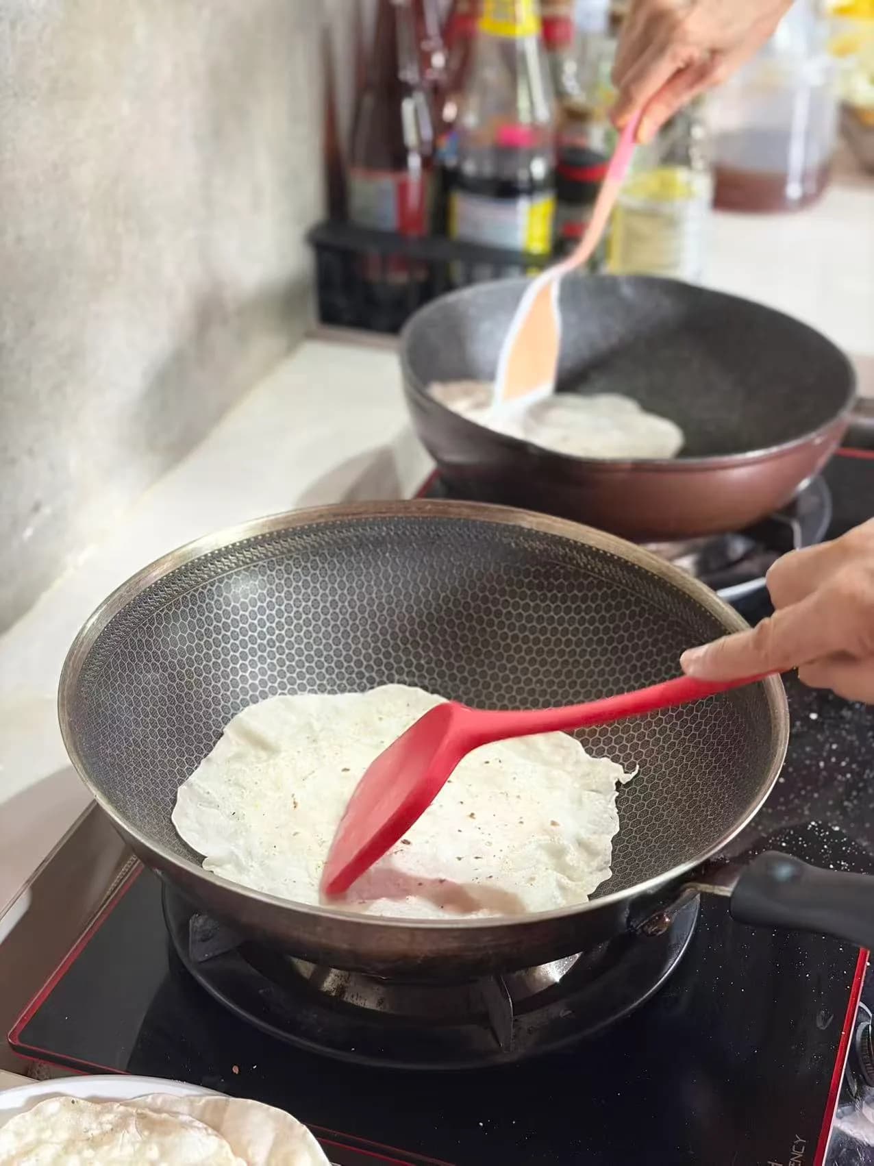 厨房炉灶上用红色铲子在不粘锅中烹饪白色食材