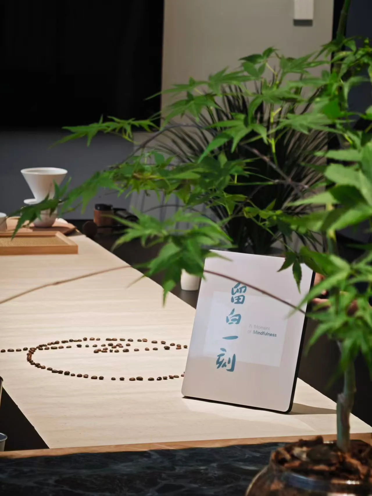 木桌上展示正念冥想用品,包括念珠、书籍、茶杯和绿色植物
