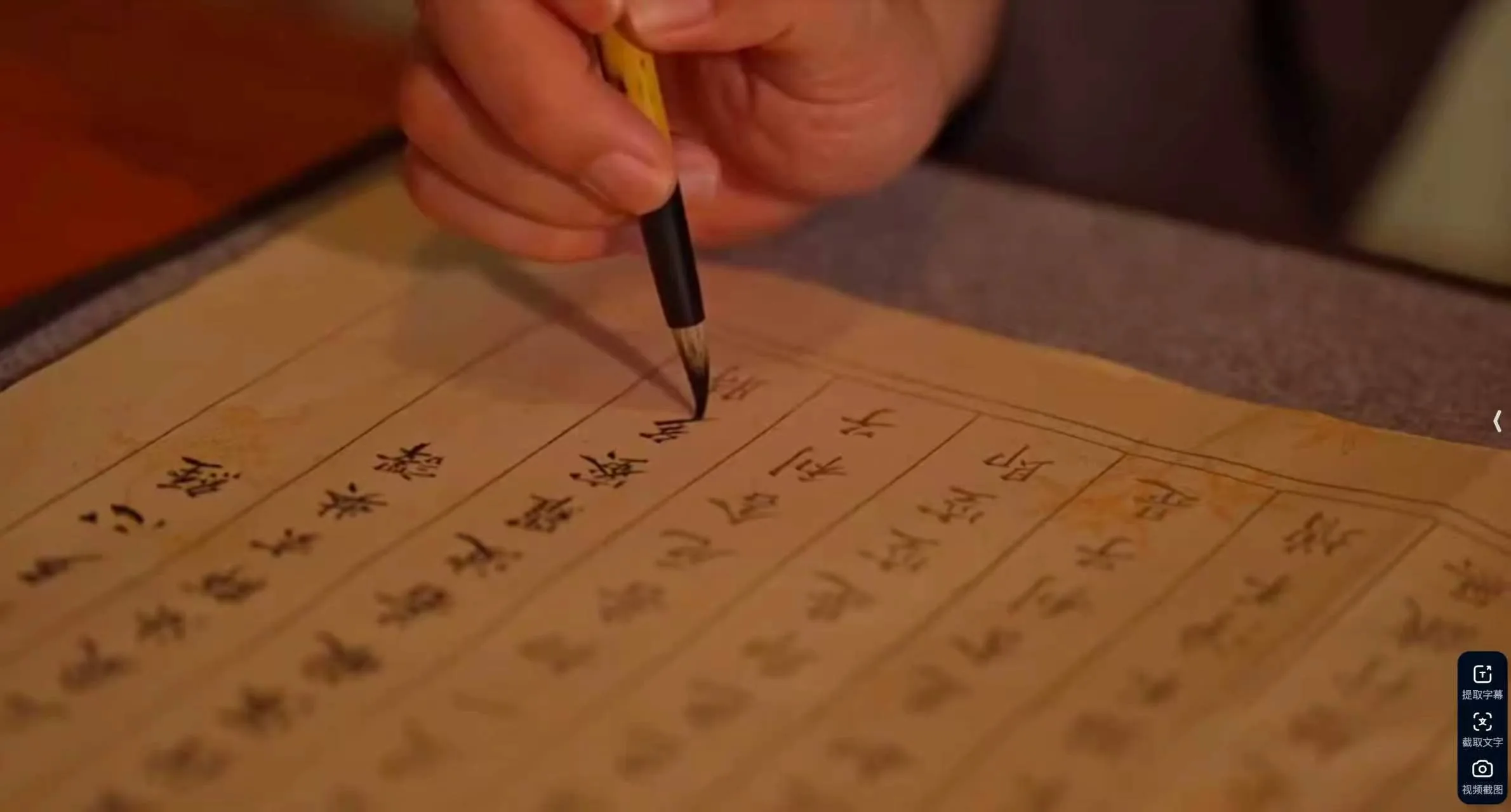 Hand holding a calligraphy brush writing Chinese characters on cream-colored rice paper
